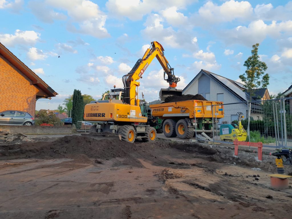 Bagger hebt Erde aus und hebt es auf einen Kipper